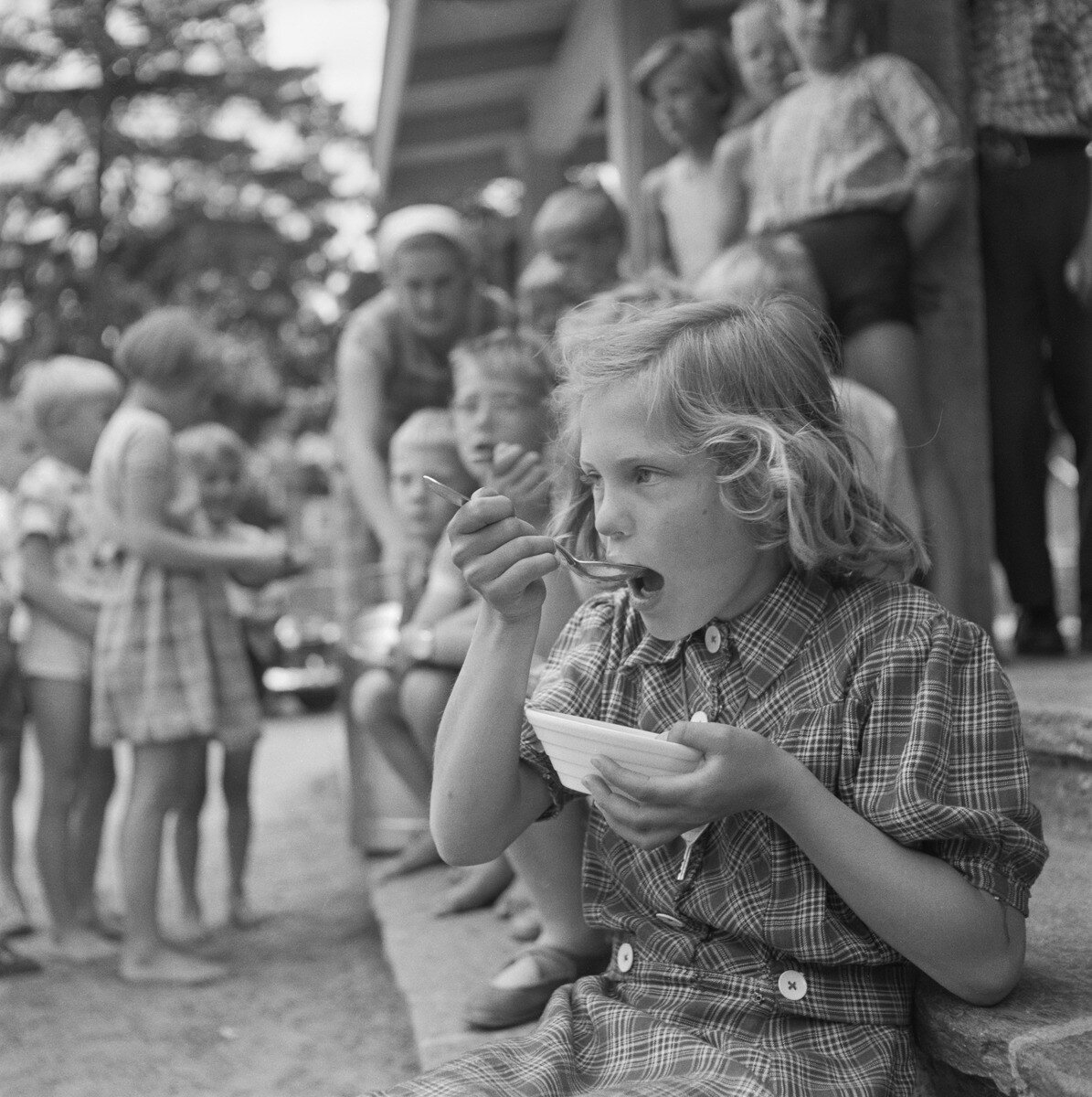 Kuva 3. Lapset leikinohjaajien hoivissa. Lapset osallistuvat puistoruokailuun leikkipuistossa kesällä 1955 todennäköisesti Käpylän Kimmon leikkikentällä. Kuvaaja Saarinen, UA. JOKA, Museovirasto.