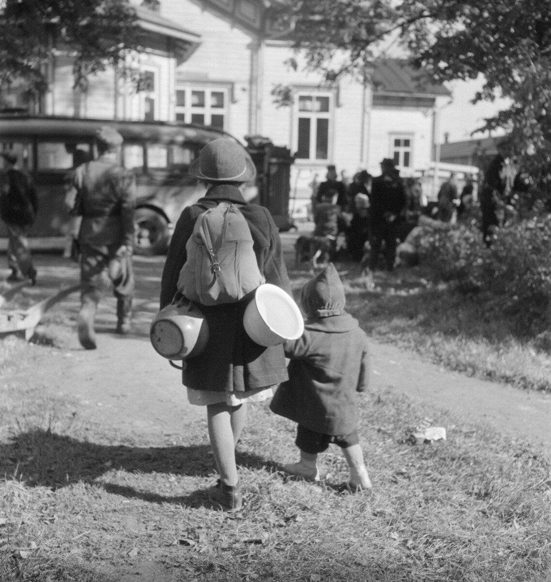 Evakoita Jaakkiman asemalla kesällä 1944. Kuten kuvastakin näkyy, auttoivat lapset voimiensa ja kykyjensä mukaisesti tavaroiden ja esineiden kantamisessa. Kiiressä kotiin jouduttiin jättämään tärkeitäkin muistoesineitä, esimerkiksi valokuvia, ja lapsille tärkeitä leluja. Kuvalähde: Pekka Kyytinen, 1944, Museovirasto.