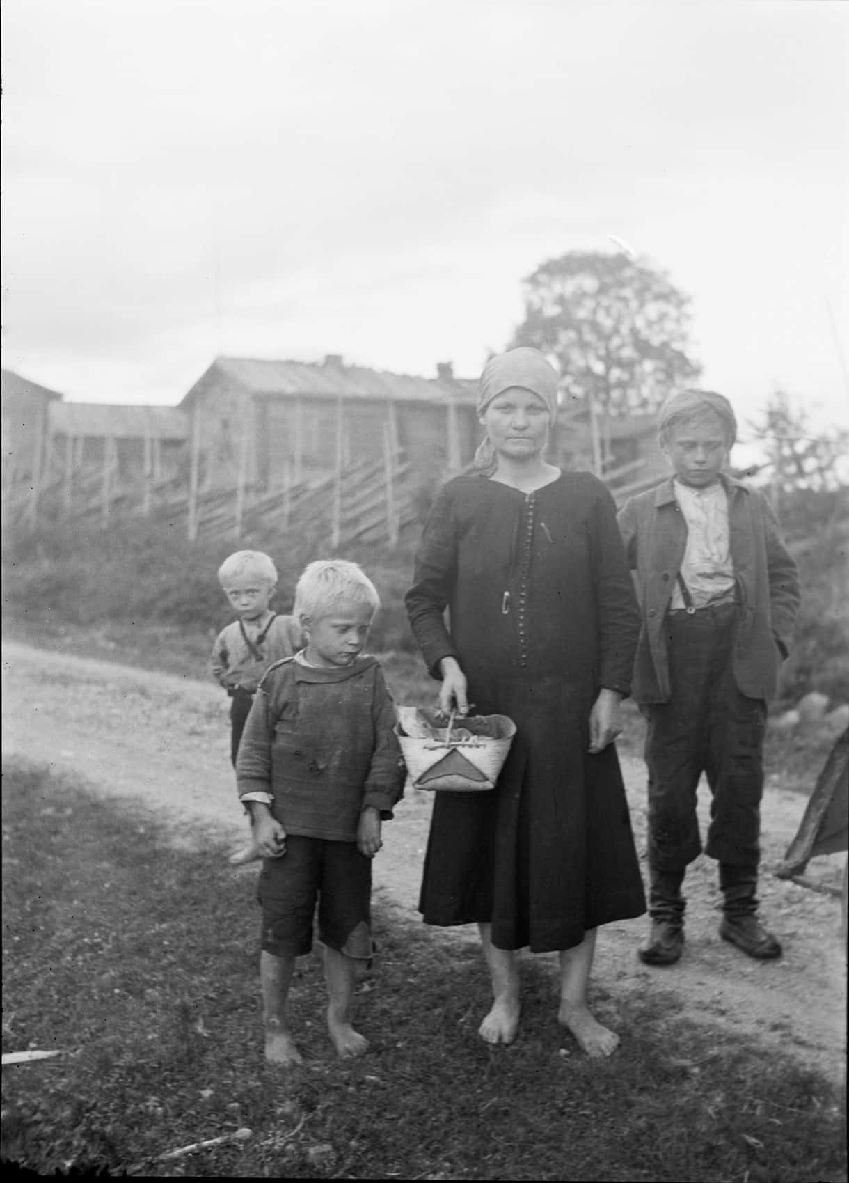 Äiti kolmen lapsensa kanssa maantiellä, paljain jaloin. Suomen valokuvataiteen museo, 1920–1939.