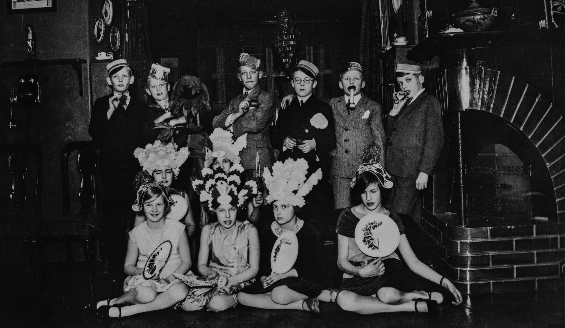 Joukko juhla-asuihin pukeutuneita lapsia poseeraa kodin sisätiloissa Helsingissä vuonna 1930.